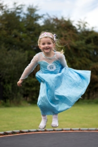 Als Eiskönigin Elsa verkleidetes Mädchen springt auf einem Trampolin